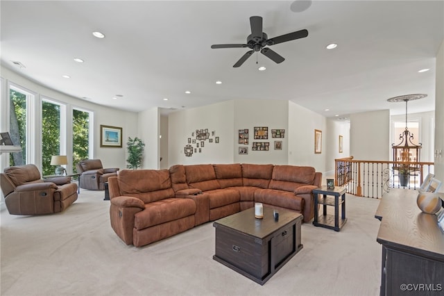 carpeted living room with ceiling fan with notable chandelier