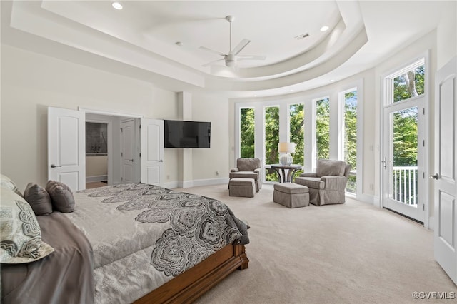 carpeted bedroom featuring access to exterior, a high ceiling, ceiling fan, and a raised ceiling