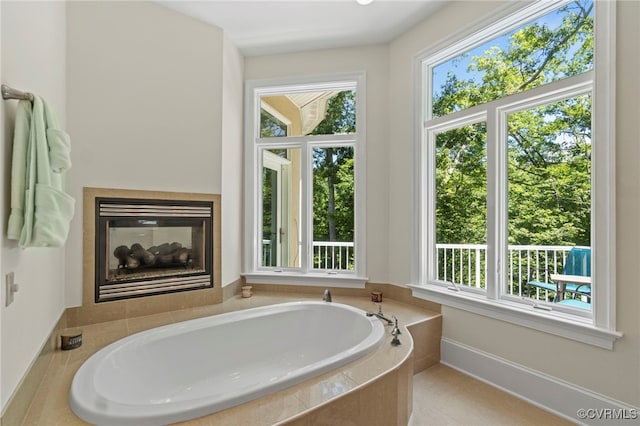 bathroom with a relaxing tiled tub and a healthy amount of sunlight