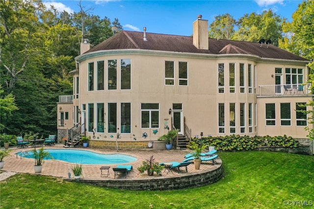 back of property with a patio area, a yard, and a balcony