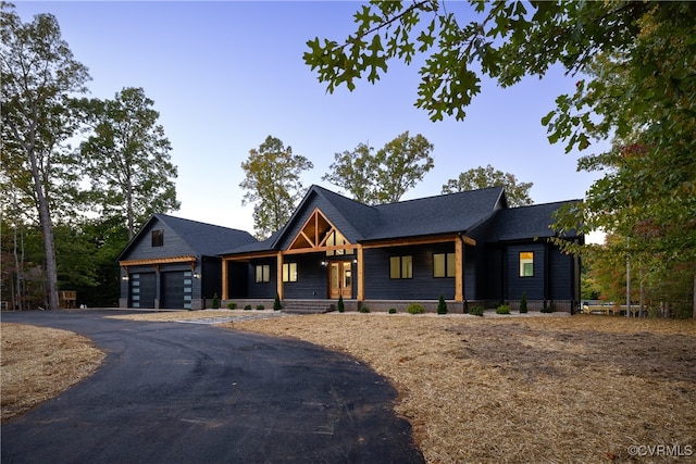 modern farmhouse style home featuring a garage, covered porch, and aphalt driveway