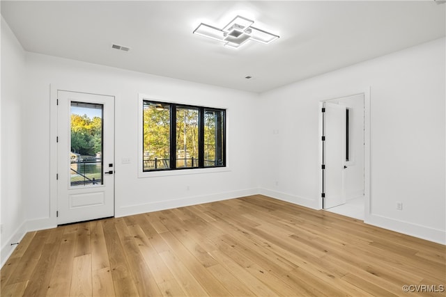 spare room with light wood finished floors, baseboards, and visible vents