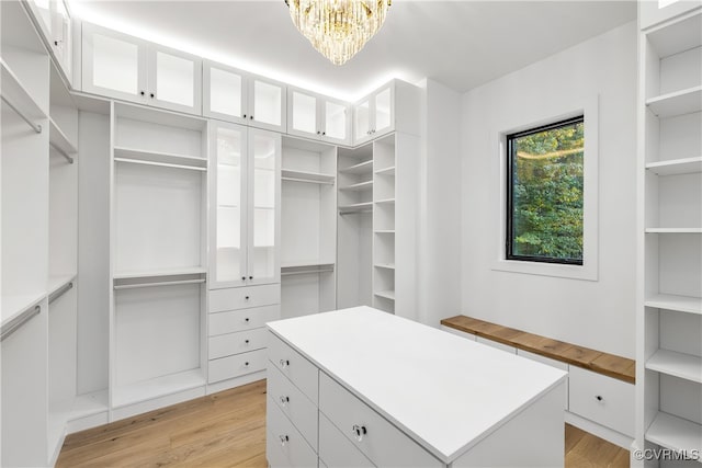 spacious closet featuring a chandelier and light wood-type flooring