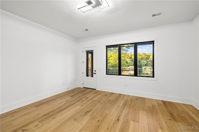 unfurnished room featuring light wood-style flooring, visible vents, and baseboards