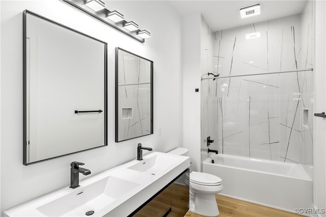 full bathroom with double vanity, wood finished floors, a sink, and toilet