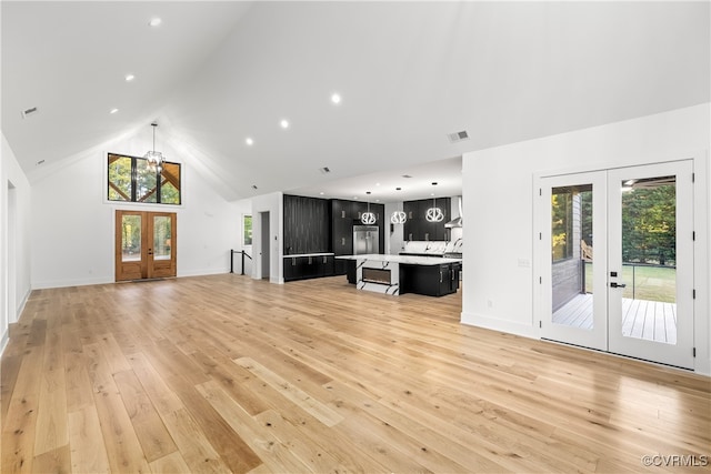 unfurnished living room with baseboards, visible vents, french doors, light wood-type flooring, and high vaulted ceiling