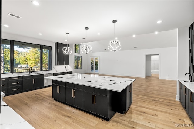 kitchen with a center island, visible vents, light wood-style floors, dark cabinets, and dishwasher