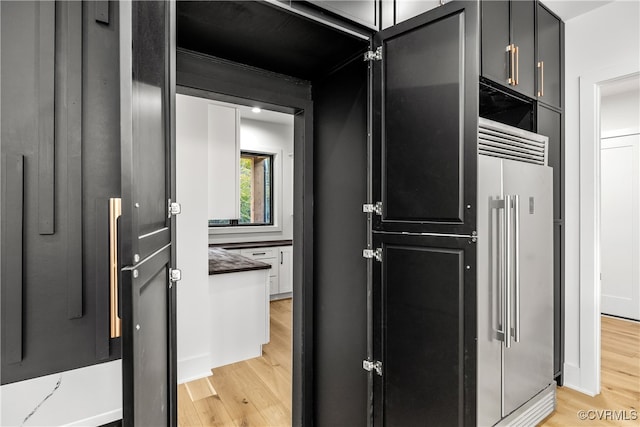 kitchen featuring light wood finished floors, high quality fridge, and dark cabinets