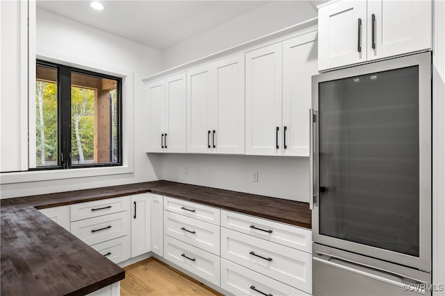 kitchen featuring light wood finished floors, stainless steel refrigerator, white cabinetry, wooden counters, and recessed lighting