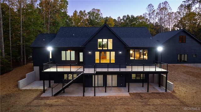 back of property featuring a patio, a shingled roof, stairway, and a wooden deck