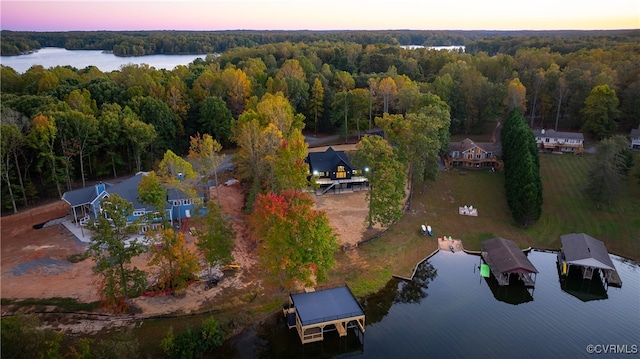 aerial view at dusk with a water view and a forest view