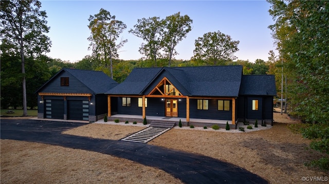 view of front of home featuring aphalt driveway, covered porch, and an attached garage