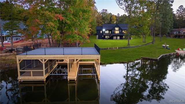 view of dock with a water view, a lawn, and boat lift