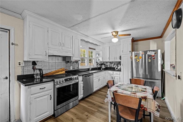 kitchen featuring dark wood-type flooring, white cabinetry, appliances with stainless steel finishes, and tasteful backsplash