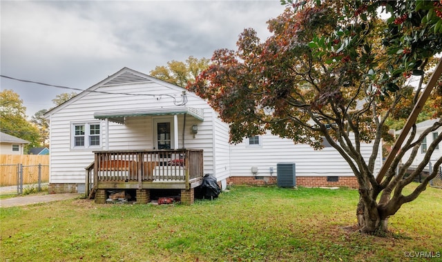 back of house with central AC unit, a wooden deck, and a lawn