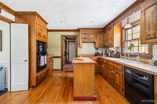 kitchen featuring a center island, black appliances, sink, light wood-type flooring, and a textured ceiling