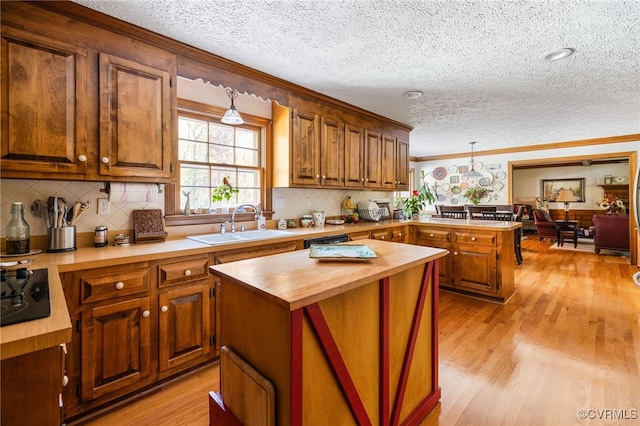 kitchen with light hardwood / wood-style flooring, hanging light fixtures, butcher block counters, and sink