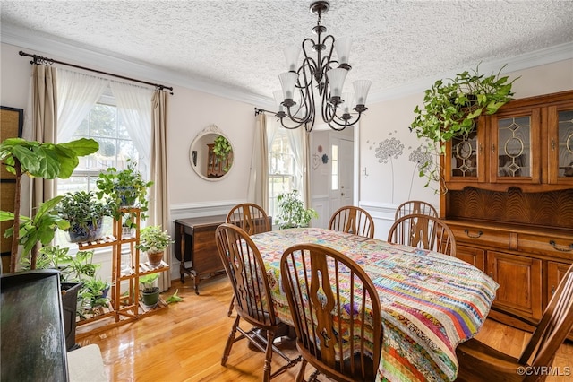 dining area featuring a textured ceiling, crown molding, and light hardwood / wood-style flooring