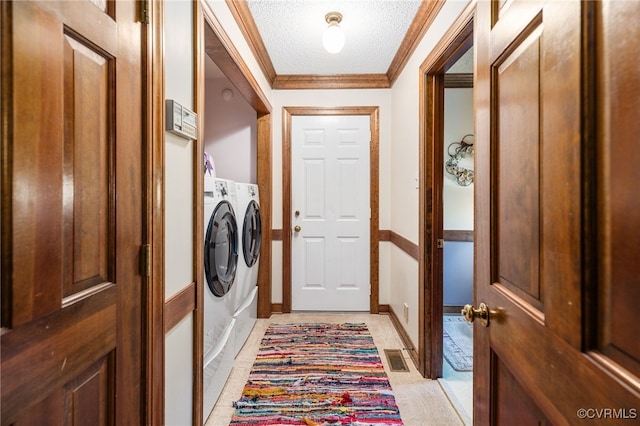 laundry room with washing machine and dryer, crown molding, light tile patterned floors, and a textured ceiling