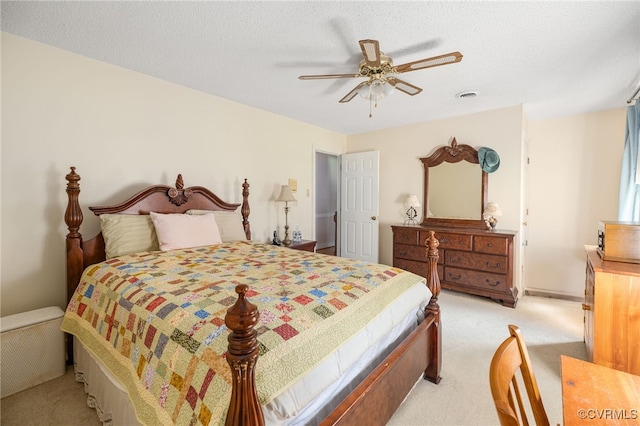 bedroom featuring ceiling fan, light carpet, and a textured ceiling