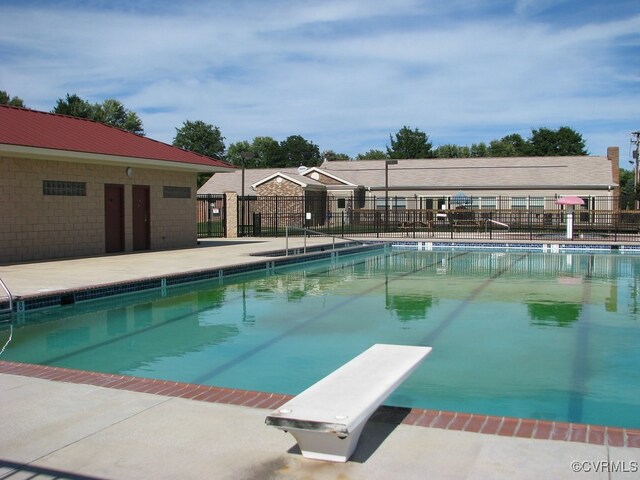 view of swimming pool with a patio and a diving board