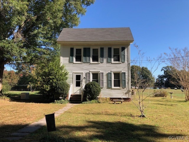 colonial home featuring central AC and a front lawn