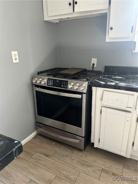 kitchen with tile countertops, stainless steel range with gas stovetop, white cabinetry, and light wood-type flooring