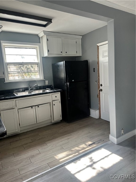 kitchen with sink, light hardwood / wood-style flooring, white cabinetry, and black refrigerator