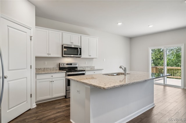 kitchen featuring white cabinets, a center island with sink, dark hardwood / wood-style flooring, appliances with stainless steel finishes, and light stone countertops