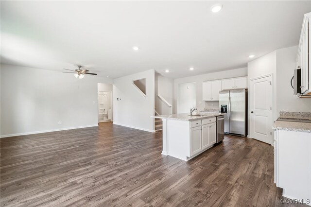 kitchen with dark wood-type flooring, an island with sink, stainless steel appliances, white cabinetry, and ceiling fan