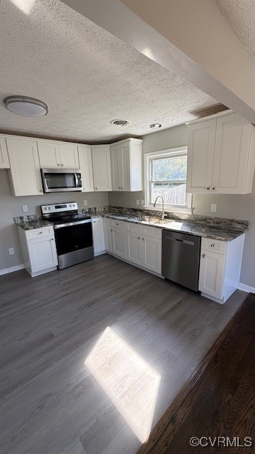 kitchen with dark hardwood / wood-style floors, stainless steel appliances, sink, white cabinetry, and a textured ceiling