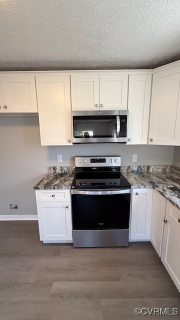 kitchen featuring dark stone countertops, appliances with stainless steel finishes, dark hardwood / wood-style flooring, and white cabinets