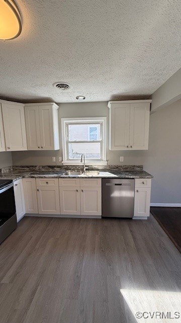 kitchen with appliances with stainless steel finishes, dark hardwood / wood-style flooring, and white cabinets