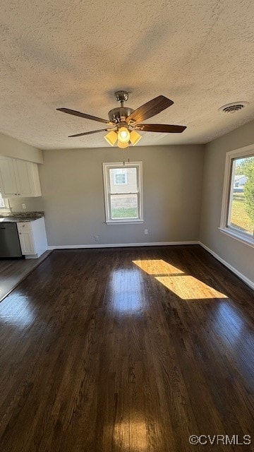 spare room featuring a textured ceiling, ceiling fan, dark hardwood / wood-style floors, and plenty of natural light