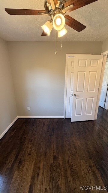 empty room with a textured ceiling, ceiling fan, and dark hardwood / wood-style flooring