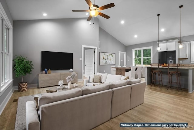 living room with ceiling fan, light hardwood / wood-style flooring, and high vaulted ceiling