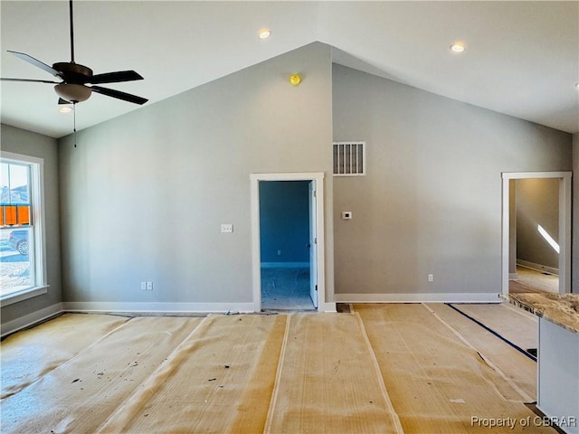 empty room with lofted ceiling, ceiling fan, and a wealth of natural light