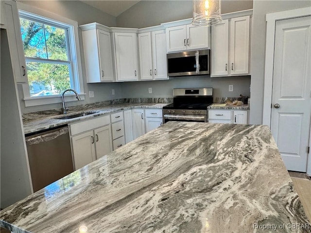 kitchen with light stone counters, sink, white cabinetry, and appliances with stainless steel finishes