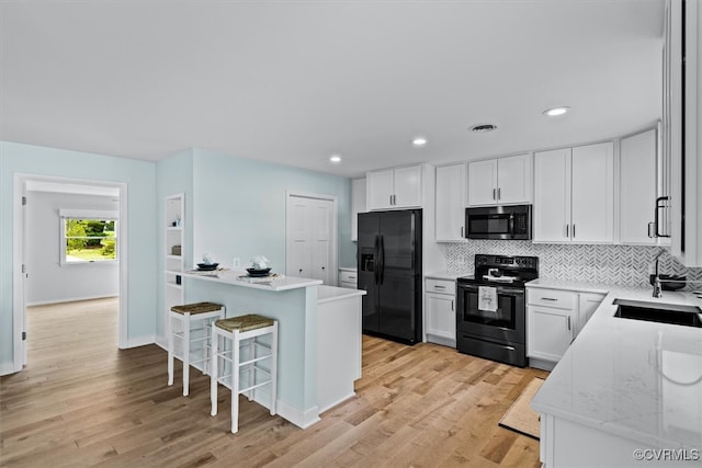 kitchen with white cabinets, appliances with stainless steel finishes, light stone countertops, light hardwood / wood-style floors, and sink