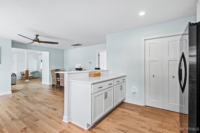 kitchen with white cabinetry, kitchen peninsula, light hardwood / wood-style flooring, and ceiling fan