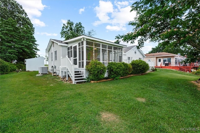 back of property featuring cooling unit, a lawn, and a sunroom