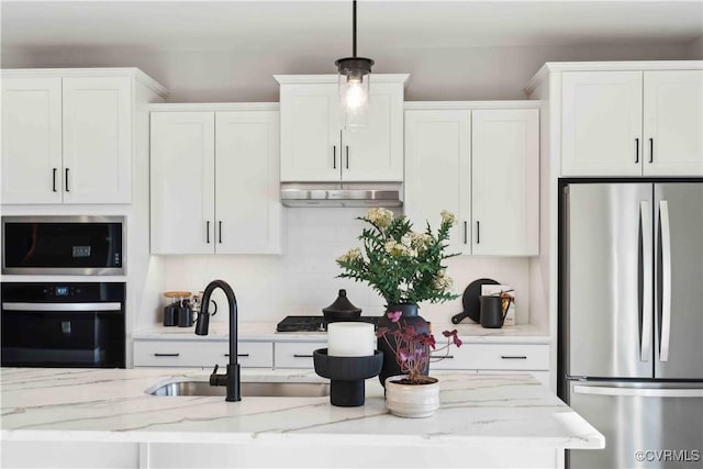 kitchen with appliances with stainless steel finishes, white cabinetry, pendant lighting, and light stone countertops