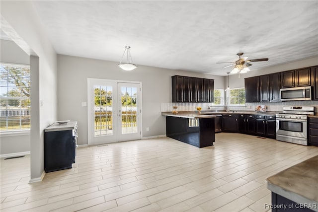 kitchen featuring decorative backsplash, dark brown cabinets, pendant lighting, appliances with stainless steel finishes, and ceiling fan