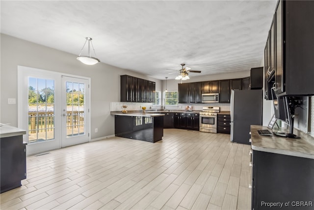 kitchen with appliances with stainless steel finishes, french doors, hanging light fixtures, ceiling fan, and dark brown cabinetry