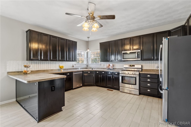 kitchen featuring butcher block countertops, appliances with stainless steel finishes, hanging light fixtures, and light wood-type flooring