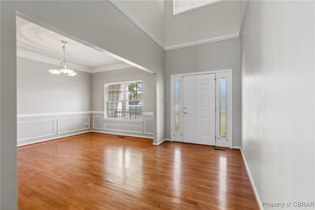 entrance foyer with ornamental molding, hardwood / wood-style floors, and a chandelier