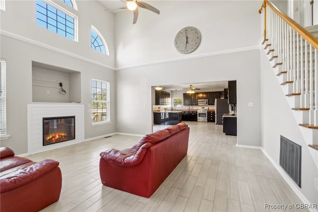 living room with light hardwood / wood-style floors and a towering ceiling