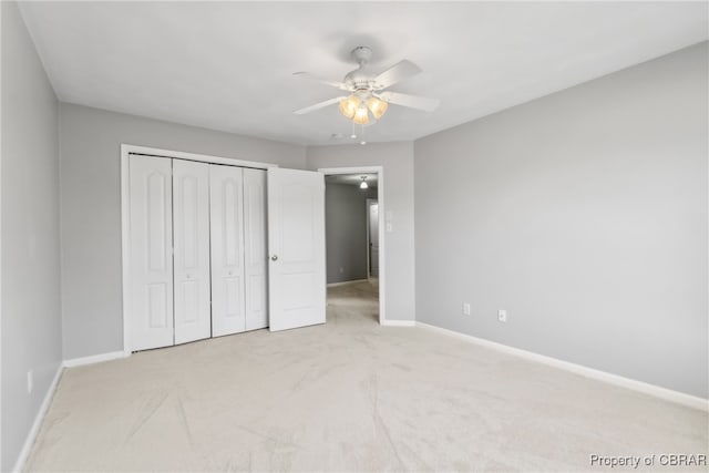 unfurnished bedroom featuring light carpet, a closet, and ceiling fan