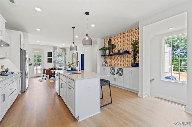 kitchen featuring white cabinets, light hardwood / wood-style floors, sink, and an island with sink