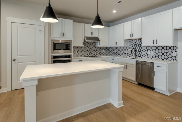 kitchen featuring white cabinetry, stainless steel appliances, light hardwood / wood-style flooring, and pendant lighting